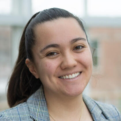 headshot of woman with brown eyes and brown hair in ponytail smiling